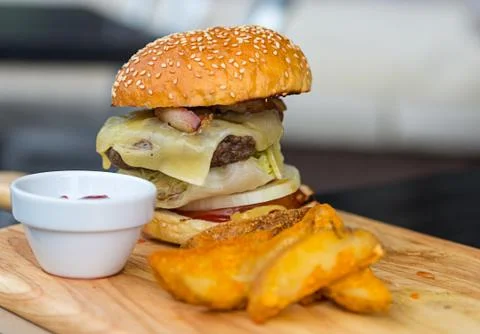 Appetizing hot burger with beef chops melted cheese and vegetables sesame bun Stock Photos