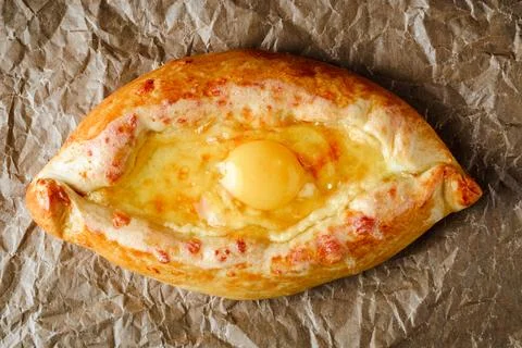 Appetizing khachapuri on parchment for baking with egg inside. Georgian cuisi Stock Photos