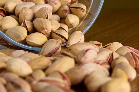 Appetizing large pistachio nuts in shell are scattered on table made glassware Stock Photos