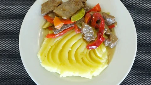 Appetizing mashed potatoes with pieces of stew and vegetables. White spinning 库存影片 114309803