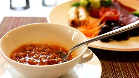 Appetizing meal featuring bowl of beans with spoon alongside plate of baked Stock Photos