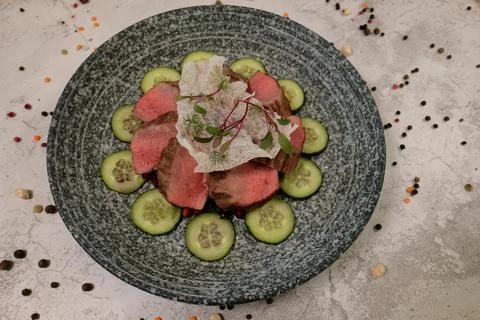 Appetizing medium-rare steak salad with cucumbers, top view on grey plate a.. Foto stock