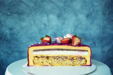 Appetizing mousse cake cut decorated with strawberries, blueberries and a pom Stock Photos
