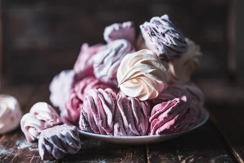 Appetizing multi-colored zephyr on a plate on a wooden table. Tea drinking co Stock Photos
