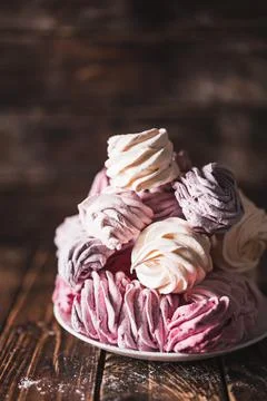 Appetizing multi-colored zephyr on a plate on a wooden table. Tea drinking co Stockfoto's