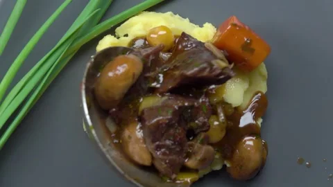 Appetizing pieces of meat bourguignon fall on mashed potatoes in a plate Video stock 315417425