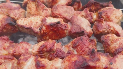 Appetizing pieces of roasted meat on spit are roasted on fire in open air a.. Stock Footage 260165612