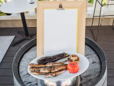 An appetizing portion of fried fish with mushrooms and pepper is on the barrel Stock Photos