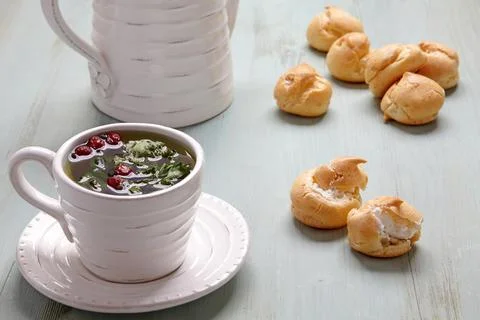 Appetizing profiteroles with whipped cream and a cup of herbal tea Stock Photos