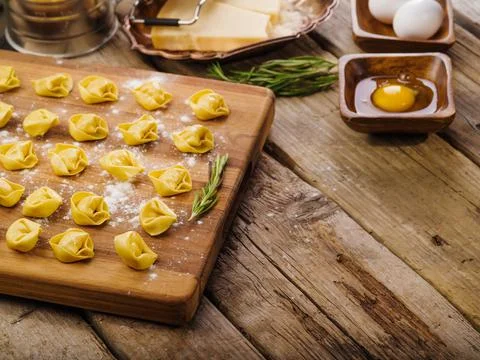 Appetizing raw handmade dumplings on a cutting board with a sprig of rosemary Stock Photos