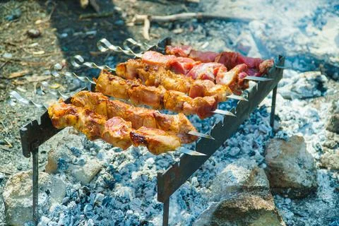 Appetizing raw meat kebab is cooked on the grill on the wood, in the open air Stock Photos