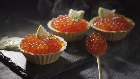 Appetizing red caviar in tartlets on a black wooden table. Steam is moving above Stock Footage 157681551