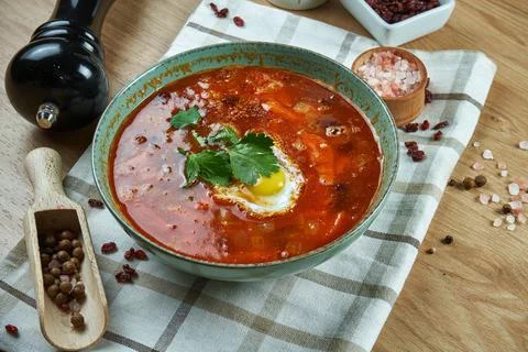 Appetizing red soup on meat broth with vegetables and quail egg. Close up vie Stock Photos
