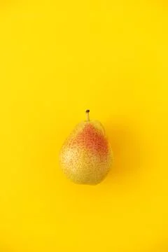 Appetizing ripe pear with red side on a yellow background. Stock Photos