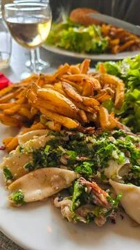 Appetizing roasted baby squid chipirones with garlic and parsley, fried potatoes Stock Photos