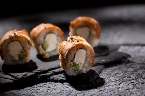 Appetizing rolls on a textured black background. Japanese food concept. Close Stock Photos