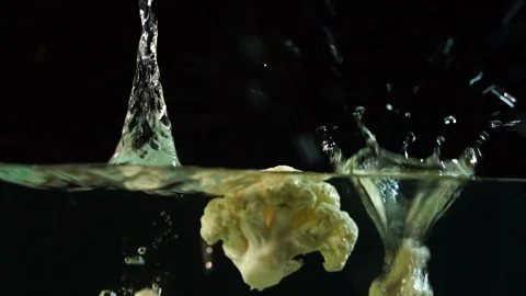 An appetizing slice of cauliflower beautifully falls into the water with bubbles Stock Footage 116018402