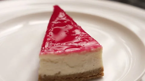 Appetizing slice of creamy cheesecake with a shiny strawberry jelly topping Stock Footage 339152595