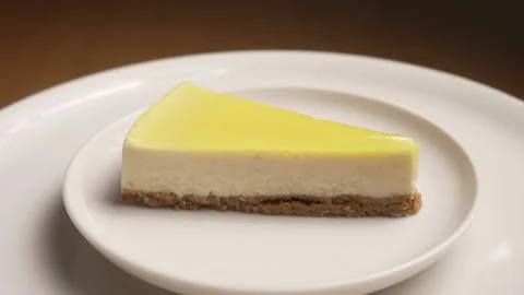Appetizing slice of creamy lemon cheesecake with a biscuit base Stock Footage 333459141