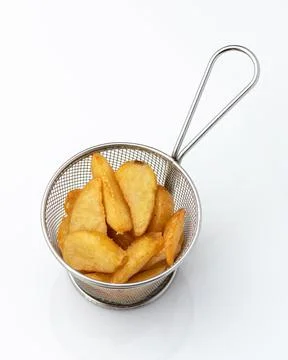 Appetizing snack. Crispy deep-fried potato slices in metal sieve or colander Stock Photos
