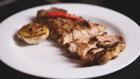 Appetizing steak on a white plate with tomatoes and chili Stock Footage 102870572