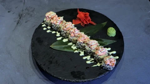 Appetizing sushi maki rotates on the black plate. Japanese menu presentation. Video stock 132413151