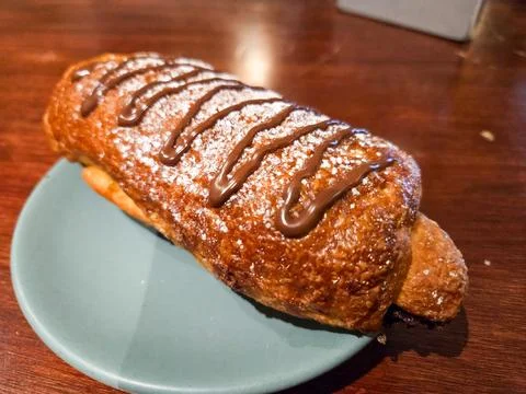 Appetizing sweet bread roll topped with chocolate sauce and powdered sugar Stock Photos