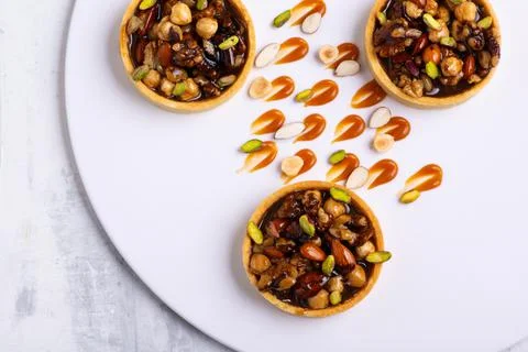 Appetizing tartlets stuffed with hazelnuts walnuts covered with a layer of liqui Stock Photos