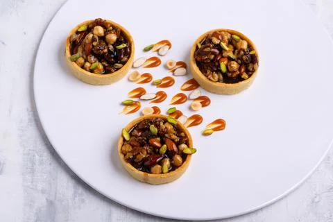 Appetizing tartlets stuffed with hazelnuts walnuts covered with a layer of liqui Foto stock