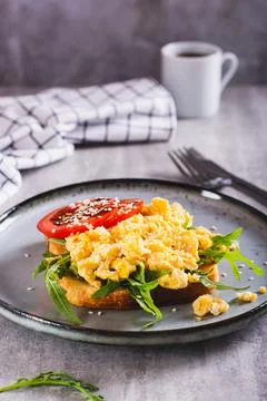 Appetizing toast with scrambled egg, tomato and sesame seeds on a plate ver.. Stock Photos