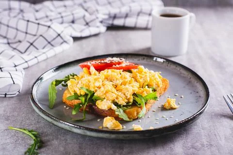 Appetizing toast with scrambled egg, tomato and sesame seeds on a plate Stock Photos