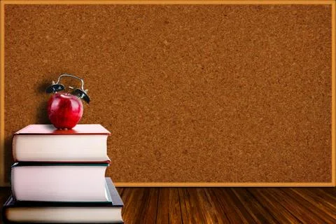 Apple Alarm Clock on Stack of Books and Corkboard Background Stock Photos