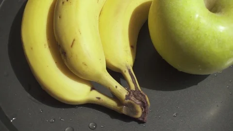 Apple and bananas rotate on a baking sheet slow motion Stock Footage 90255956