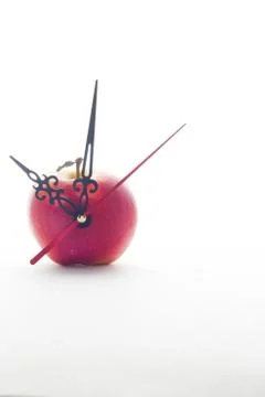 Apple and clock hands on white background Stock Photos