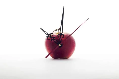 Apple and clock hands on white background Stock Photos