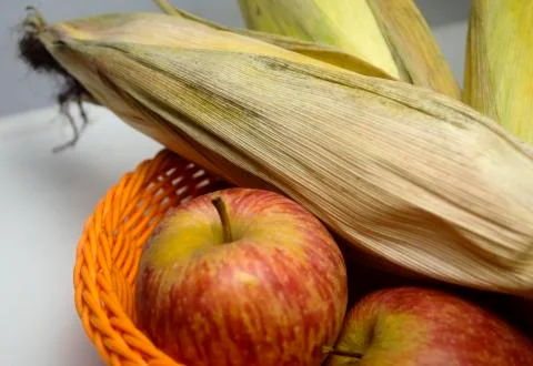 Apple and leafed corn on a blurred isolated background Stock Photos