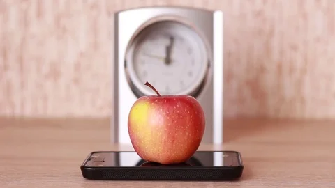 Apple and smartphone in front of the clock Vídeos de archivo 83030201