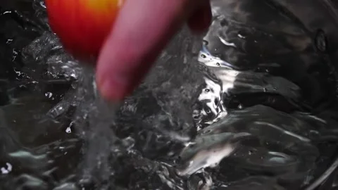 Apple being picked out of water in slow motion splashing  Video stock 151060197