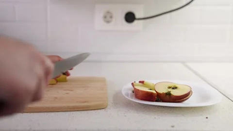 Apple being sliced with knife, Fruit meal preparation in kitchen, Wooden board Stock Footage 313205595