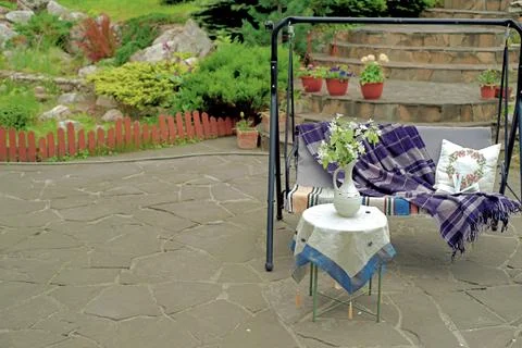 Apple blossoms on a table in front of a sofa swing in the courtyard of a co.. Stock Photos