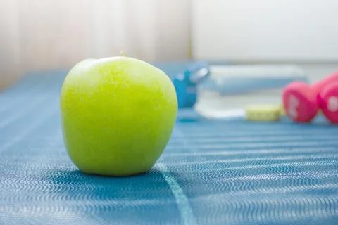 Apple on a blue mat on the background of a bottle of water, a tape measure an Stock Photos