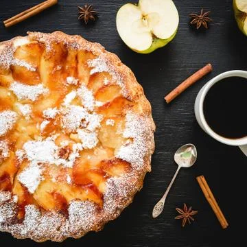 Apple cake with coffee mug, apple fruit, cinnamon and mimosa flowers on dark. Foto stock
