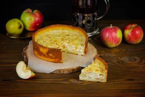 Apple cheesecake on a rustic kitchen with a tea kettle on the wooden dark bac Stock Photos