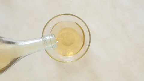 Apple cider vinegar is poured from the bottle into a glass bowl Video stock 252137673