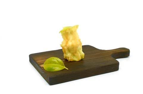 An apple core and a small green leaf lie on a wooden cutting board Stock Photos