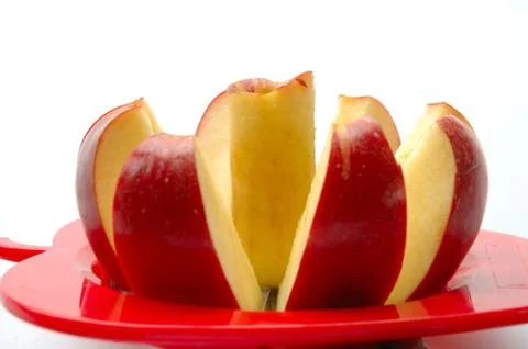Apple cut into pieces with special cutting device on white background Stock Photos