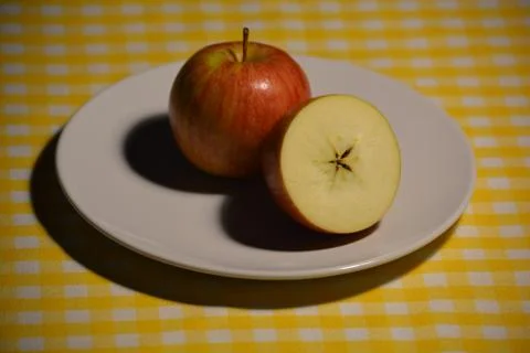 An apple a day. One and a half on a white plate Stock Photos