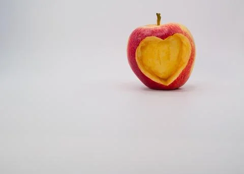 Apple with empty heart shape carved inside on white background Stock Photos