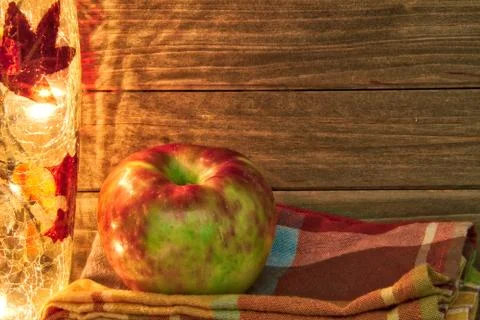 Apple in a fall theme with light and napkin and a wood background providing c Stock Photos
