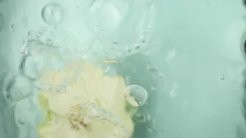 Apple half drops into water from above creating a splash. As the apple submerges Stock Footage 272388754